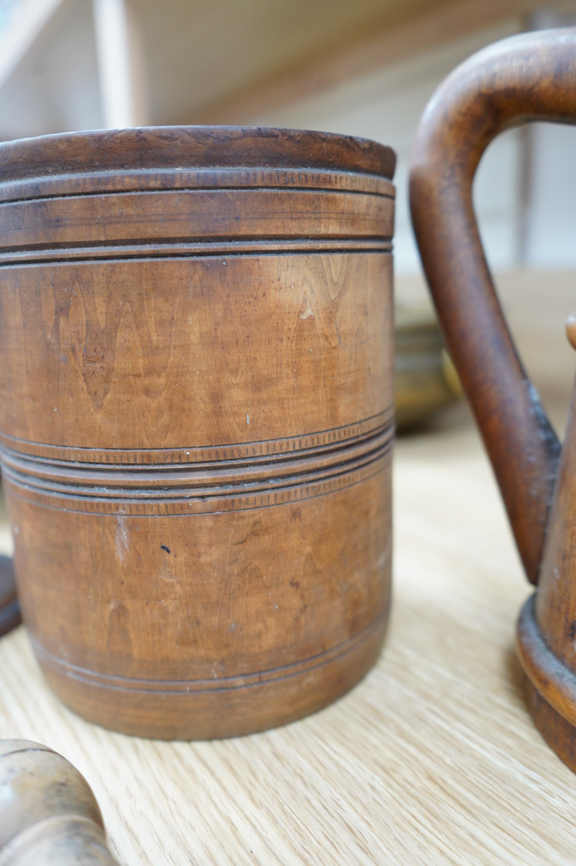 A pair of staved beech flagons, 23cm high, a wooden pestle and mortar, 17.5cm, and turned wood lidded bowl, 18cm (5). Condition - fair